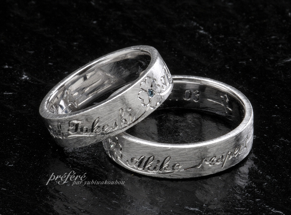 放射線状テクスチャーに四つ葉のクローバーと名前を入れた結婚指輪はオーダーメイド